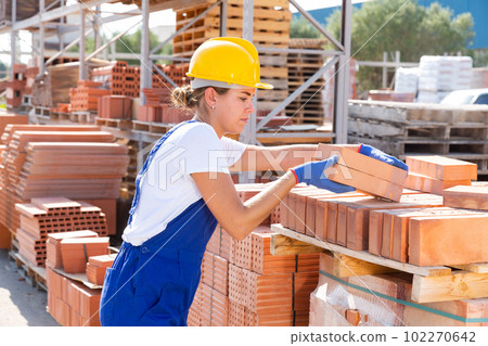 Female worker with bricks in warehouse 102270642