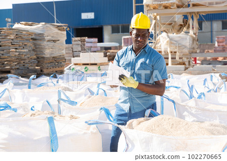 Man standing amongst bags in construction material storage 102270665