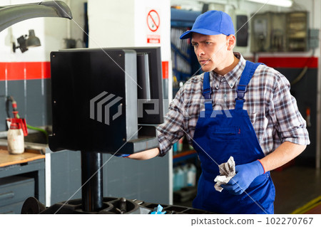 Mechanic worker balancing tire with wheel balancing machinery Mechanic worker balancing tire with wheel balancing machinery 102270767