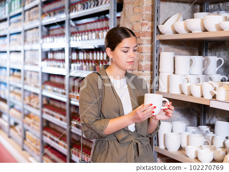 Young woman chooses pottery clay cup 102270769