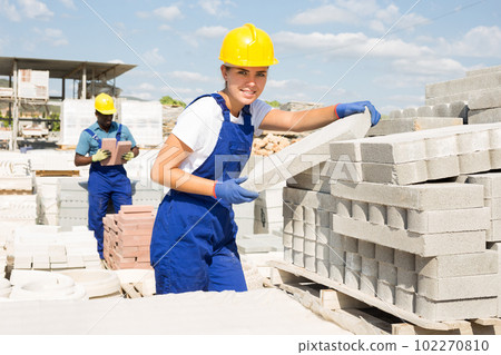 Woman checking quality of bricks at construction store 102270810