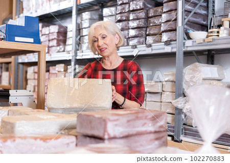 Elderly woman chooses pottery clay in shop Elderly woman chooses pottery clay in shop 102270883