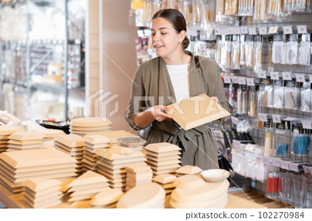 Woman chooses various wooden molds for future clay molding in her workshop 102270984