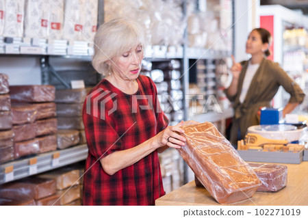 Elderly woman buys briquettes with red clay in specialized store Elderly woman buys briquettes with red clay in specialized store 102271019