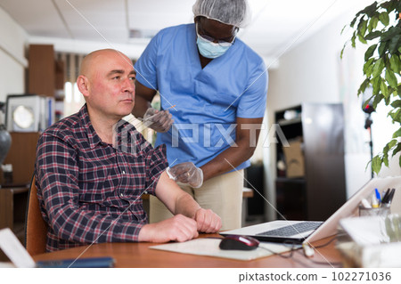 Entrepreneur getting vaccinated by african american doctor in office Entrepreneur getting vaccinated by african american doctor in office 102271036