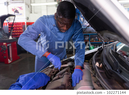 Professional american mechanic man in uniform repairing car engine Professional american mechanic man in uniform repairing car engine 102271144
