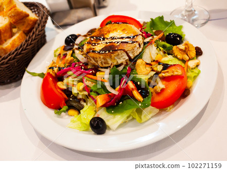 Fried goat cheese salad with vegetables, greens, nuts and raisins 102271159