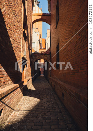 Elblag, Poland. Medieval alleyway in Old Town of Elblag city in Poland. Narrow cobblestone passage between tenement houses called The Church Path. View of City of Architecture famous popular tourist 102272131