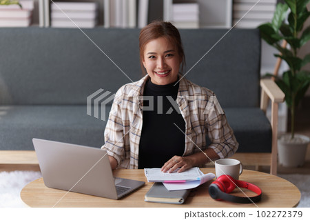 Woman sits on sofa at home, studying and analyze house bills and submitting tax forms. Woman sits on sofa at home, studying and analyze house bills and submitting tax forms. 102272379