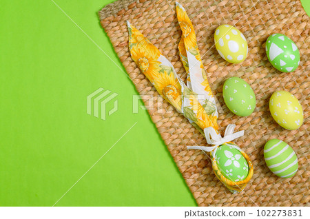 Happy Easter holiday greeting card design concept. Colorful Easter Eggs and spring flowers on pastel green background. Flat lay, top view, copy space. 102273831