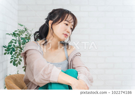 Fashionable Asian woman sitting on a chair and relaxing Fashionable Asian woman sitting on a chair and relaxing 102274186