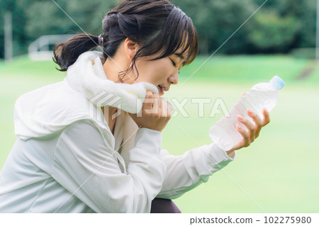 Side profile of Asian woman hydrating during exercise break Side profile of Asian woman hydrating during exercise break 102275980