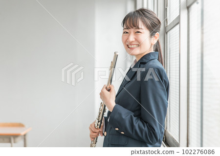 Asian high school girl in brass band playing flute in school classroom Asian high school girl in brass band playing flute in school classroom 102276086
