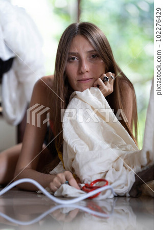 a young fashion designer girl poses next to a mannequin and holds scissors in her hands. 102276429