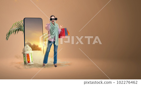 Asian Muslim woman in a headscarf looking through binoculars while holding shopping bags 102276462