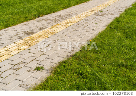 Tactile paving on pedestrian walkway with a green grass on both sides Tactile paving on pedestrian walkway with a green grass on both sides 102278108