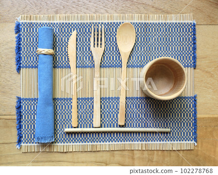 Bamboo wood cutlery, disposable fork, spoon,knife, straw and bamboo cup made of natural material on placemat 102278768