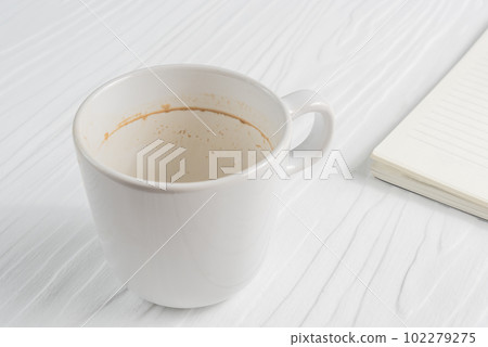 Coffee cup with coffee stains have not washed the cup placed on the white table Coffee cup with coffee stains have not washed the cup placed on the white table 102279275