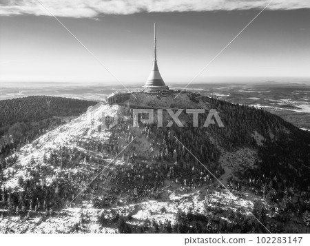 Jested mountain with modern hotel and TV transmitter on the top, Liberec, Czech Republic. Sunny winter day with snowy landscape. Aerial view from drone. Black and white photography. Jested mountain with modern hotel and TV transmitter on the top, Liberec, Czech Republic. Sunny winter day with snowy landscape. Aerial view from drone. Black and white photography. 102283147