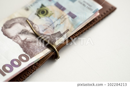 Ukrainian hryvnia money in leather money clip, wallet. Ukraine money on white background with. Currency of Ukraine. Accessories. Money, financess, economy, saving. 102284213
