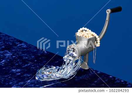 Portrait with meat grinder for cooking food full of pearl, jewelry over dark blue studio background. Rich people menu 102284293