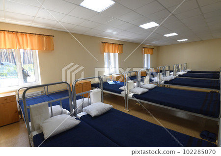 Room of barrack for soldiers well-made beds, nightstands, benches and TV set on the wall. Staroe, Ukraine Room of barrack for soldiers well-made beds, nightstands, benches and TV set on the wall. Staroe, Ukraine 102285070