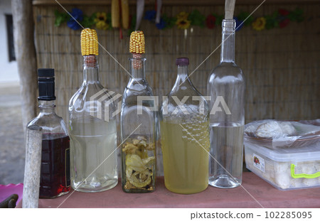 Bottles with traditional Ukrainian drink samogon sealed in traditional way and placed on a table Bottles with traditional Ukrainian drink samogon sealed in traditional way and placed on a table 102285095