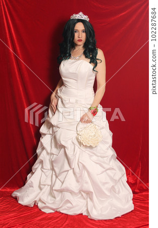 Woman Wearing Corset Style Ball Gown Wedding Dress on Red Velvet Background Woman Wearing Corset Style Ball Gown Wedding Dress on Red Velvet Background 102287684
