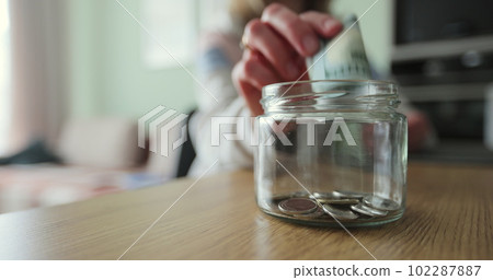 Woman and man hands putting money in a glass jar. Family saving money. Money box. 102287887