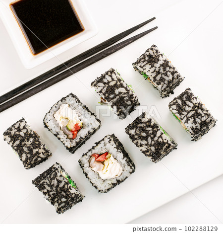 Sushi plate on white background, rolls set with black tobiko egg on white background from above. Top view of traditional japanese cuisine. Asian food with chopsticks design. 102288129