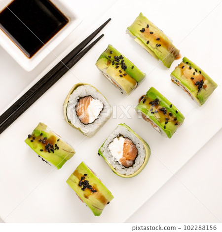 Sushi plate on white background, rolls set with cucumber on white background from above. Top view of traditional japanese cuisine. Asian food with chopsticks design. Sushi plate on white background, rolls set with cucumber on white background from above. Top view of traditional japanese cuisine. Asian food with chopsticks design. 102288156