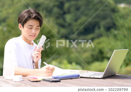 A student studying while using an electric fan outdoors A student studying while using an electric fan outdoors 102289799
