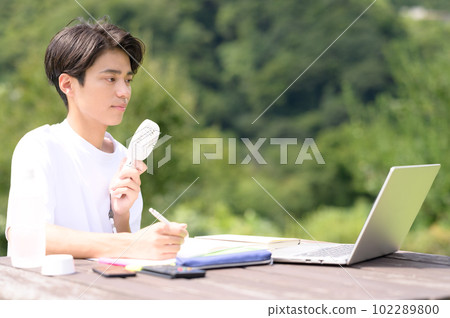 A student studying while using an electric fan outdoors 102289800