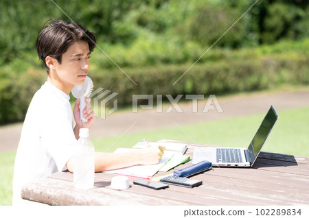 A student studying while using an electric fan outdoors 102289834
