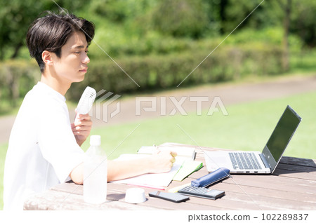 A student studying while using an electric fan outdoors 102289837