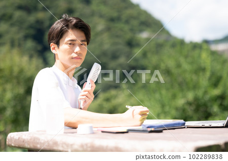 A student studying while using an electric fan outdoors 102289838