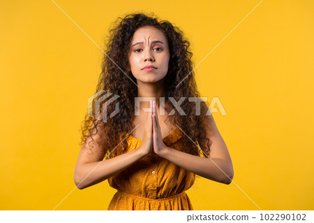Cute woman praying, begs to apologize her, she is guilty. Yellow background. Cute woman praying, begs to apologize her, she is guilty. Yellow background. 102290102