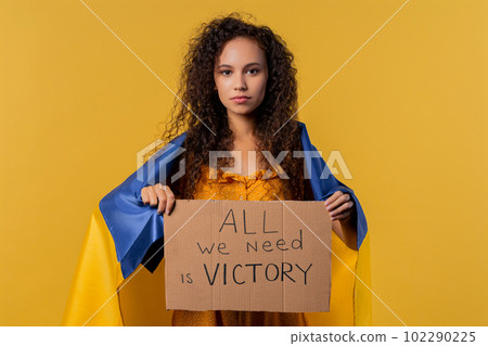 Ukrainian woman with cardboard All we need is victory on yellow background. 102290225