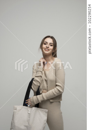 Brunette cheerful millennial woman holding white eco bag standing over white studio background. Concept of recycle for better environment. No plastic. Fashion and ecology concept. Brunette cheerful millennial woman holding white eco bag standing over white studio background. Concept of recycle for better environment. No plastic. Fashion and ecology concept. 102290254