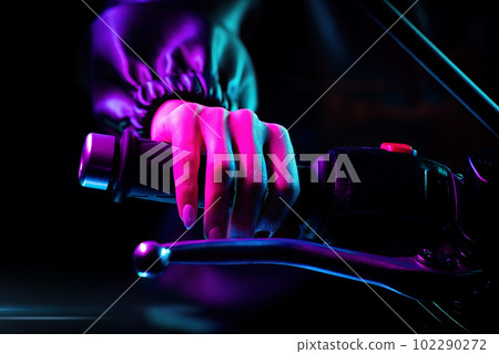 Drivers female hand twists accelerometer lever at night city. Neon light. Drivers female hand twists accelerometer lever at night city. Neon light. 102290272