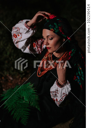 Portrait of ukrainian woman with fern at night in Carpathian mountains forest. 102290414