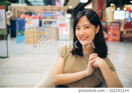 Smiling beautiful asian woman sitting in cafeteria at shopping mall. 102291224