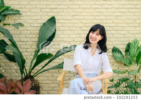Portrait beautiful young asian woman happiness sitting on yellow cement texture grunge wall brick and green plant background, Happy female is smiling on concrete, wellness people concept. Portrait beautiful young asian woman happiness sitting on yellow cement texture grunge wall brick and green plant background, Happy female is smiling on concrete, wellness people concept. 102291253