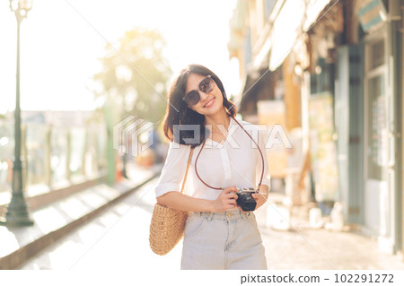 Portrait young beautiful asian woman with camera explore street on summer vacation in Bangkok, Thailand 102291272