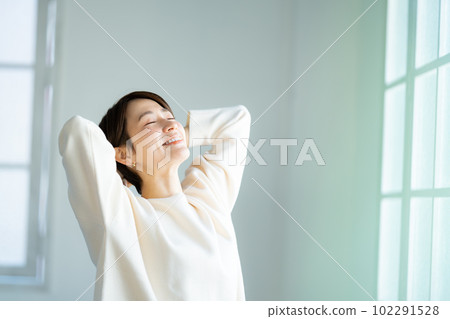 A woman in her 40s stretching by the window A woman in her 40s stretching by the window 102291528