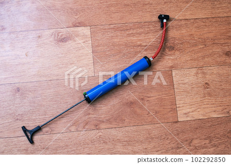 Bicycle wheel pump on wooden floor closeup 102292850
