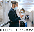 man and a woman in protective masks waiting for a train in the subway. 102293068