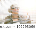 close up. serious business woman looking through office window 102293069