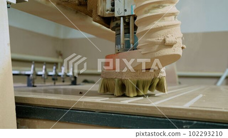 Factory for the manufacture of wooden doors. Cutting sheets of wood chipboard material. The equipment cuts a pattern on chipboard material. Factory for the manufacture of wooden doors. Cutting sheets of wood chipboard material. The equipment cuts a pattern on chipboard material. 102293210