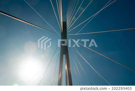 Suspension bridge support cables against a blue sky and sunbeam reflections Suspension bridge support cables against a blue sky and sunbeam reflections 102293403